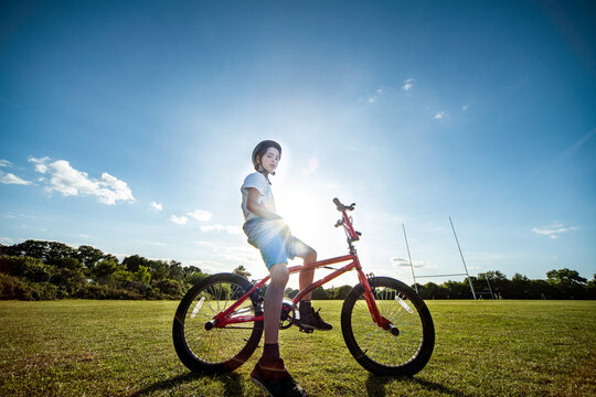 Portrait of boy sitting on his BMX bicycle, wearing cycling helmet.