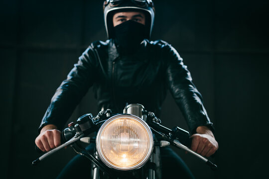 Young male motorcyclist on vintage motorcycle in garage, portrait