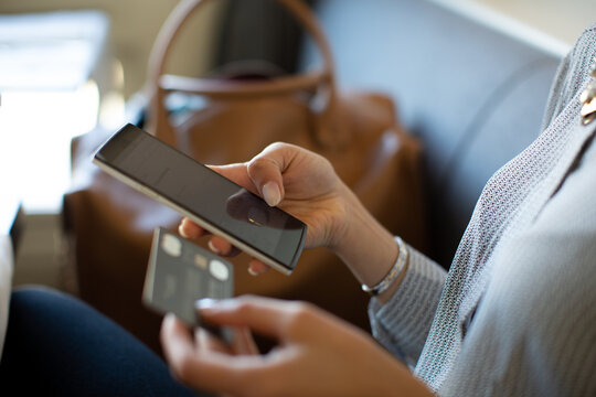 Close up of woman holding credit card and mobile phone.