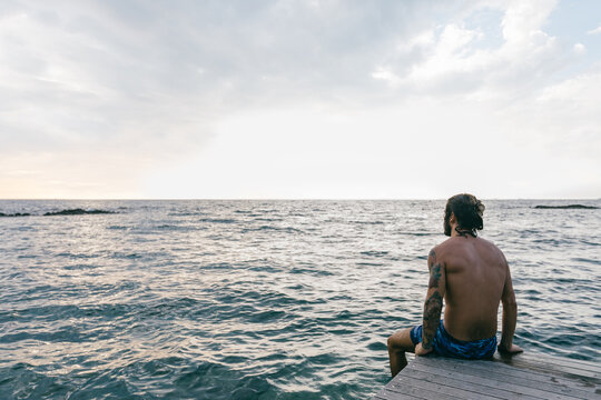 Man sitting on edge of sea