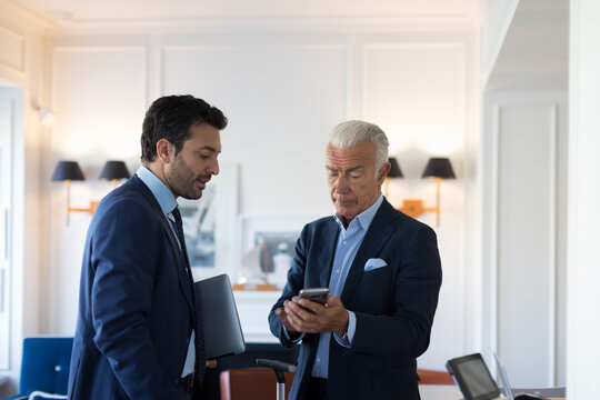 Two businessmen standing indoors, talking.