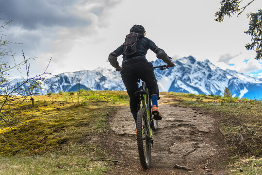 Woman mountain-biking in a forest in the Canadian mountains in British Columbia.