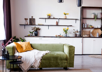 Stylish scandinavian open space with kitchen accessories,flowers and sofa.