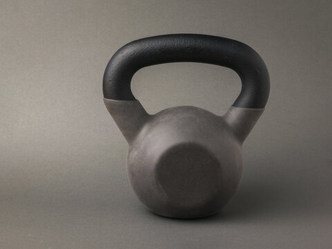 A gray sports kettlebell on a dark gray background.