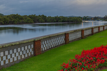 Cloudy morning waterscape with red flowers and memorial wall