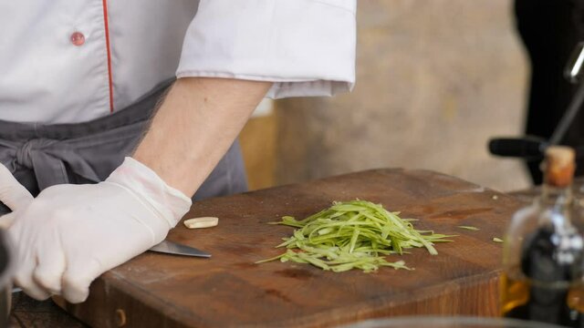 Cutting garlic with a sharp knife. The hands of the chef with a knife. Restaurant kitchen