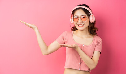 Beautiful young girl wearing pink headphones on a pink background