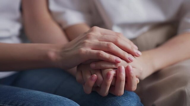  Close-up shot of two people holding hands for encouragement.