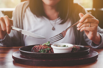 Happy asian woman enjoy eating delicious beef steak in restaurant