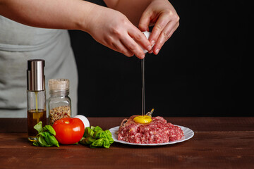 The cook breaks an egg into a fresh mince for a burger. Cooking a burger. Frozen egg movement in flight