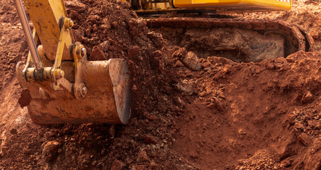 Backhoe working by digging soil at construction site. Bucket of backhoe digging soil. Crawler...