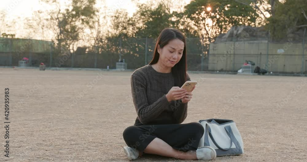 Poster Asian woman use of cellphone at sunset