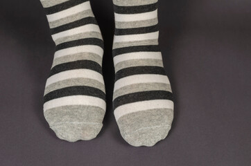 Legs in striped socks on a gray background.
