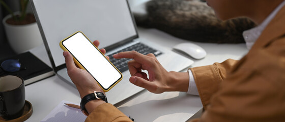 Cropped shot of young man working online with computer laptop and using mobile phone a home.