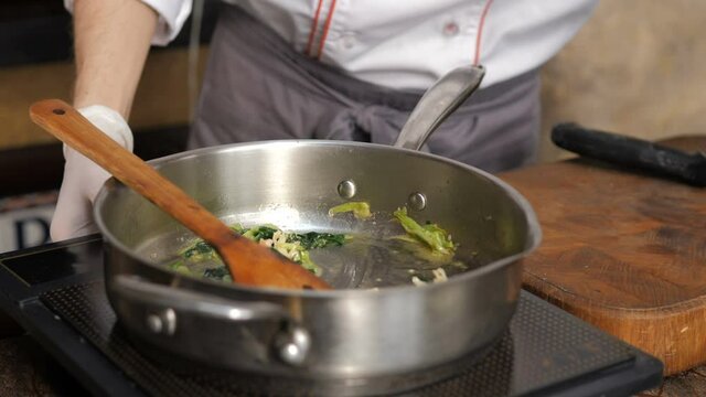 Chef frying garlic in olive oil in restaurant