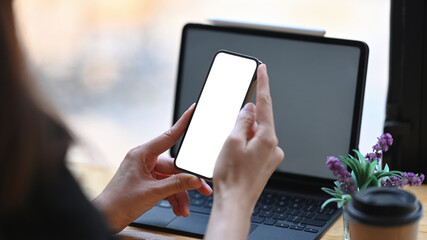Over shoulder closeup view of businesswoman working with computer tablet and using smart phone.