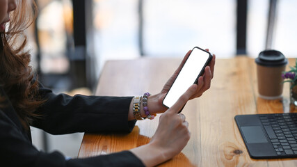 Close up view of businesswoman hands holding mock up mobile phone with blank screen.