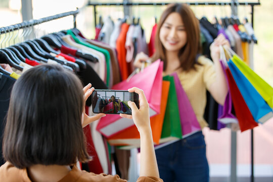 Blurred woman taking photo of girlfriend in shop