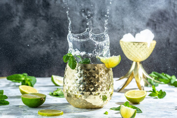 Cocktail with ice, in a copper mug with lime, ginger beer, vodka and mint. splashing Moscow mule alcoholic cocktail