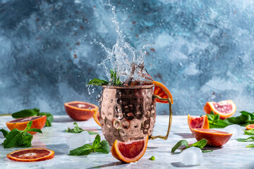 Moscow mule cocktail in copper cup with blood orange, ginger beer, vodka and mint. freeze motion...