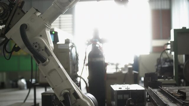 industrial 4.0 concept modern automated robot welding arm machine tool welds metal pipe and plate with bright sparks and smoke in production plant shop factort background