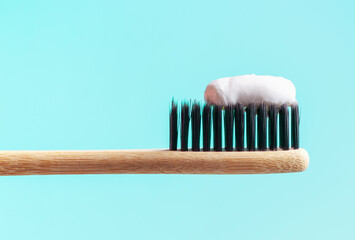 Bamboo toothbrush with toothpaste on blue background close-up.