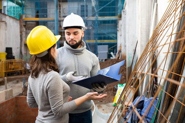 Civil engineers inspecting process of building overhaul, comparing to blueprints