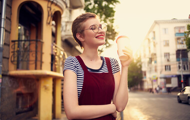 Fototapeta premium pretty woman with short hair and red lips on the street walk glass with drink