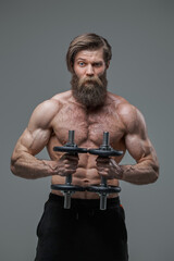 Fototapeta na wymiar Athletic man with fashionable hairstyle and dumbells in studio
