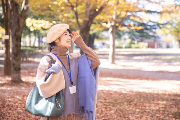 秋の公園にいるネームをつけた女性
