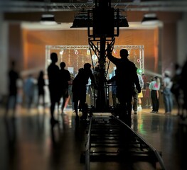 Blurred behind the scenes of music video shooting production crew team silhouette and camera equipment in studio. Soft focus. 