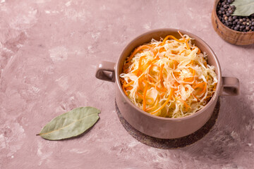 Homemade sauerkraut with carrots in a deep plate on a rustic background. Fermented product.