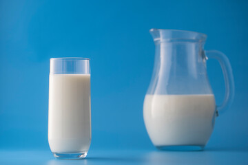 White milk in a jug and glass on a blue background. Dairy product concept