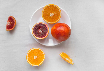 Flat lay of fresh sweet and juicy blood oranges and oranges, whole and cut on a white plate. Fresh...