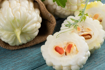 White bitter gourd fruit and green leaves on an old wood background.