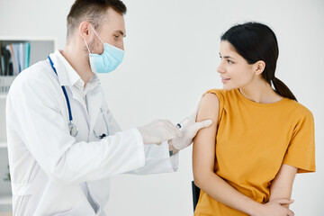 doctor tapes a shot on a woman's shoulder in a hospital infection epidemic covid 