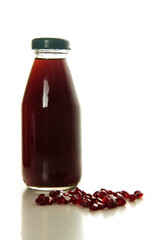 a bottle of pomegranate juice and pomegranate seeds isolated on white background