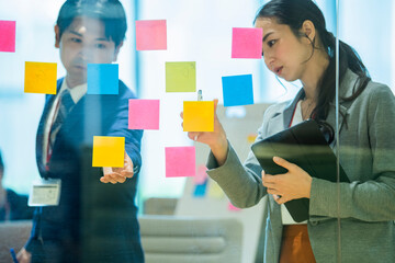 付箋にアイディアを出し合いアイディアを検討する社員たち