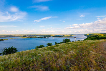 Panoramic view of the road bridge over big river and hills, slopes, steppe coast, gully, ravine on a banks