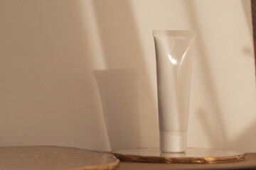 White cosmetic tube mockup on warm soft light background. Minimalism product still life. Light and...