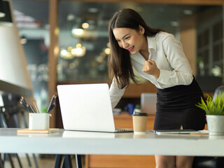 Fototapeta premium Female entrepreneur celebrating on her accomplishment while standing in workplace