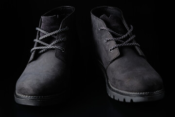 Black chukka boots captured in low key. Black mens suede shoes at black background