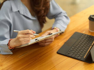 Female office worker hand working with paperwork on clipboard on wooden table