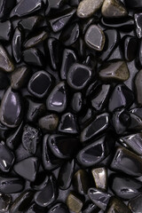Gold obsidian jewel heap on light wood texture. Pile mineral pebbles background.