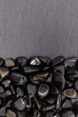 Gold obsidian jewel heap on black stone half background. Pile mineral pebbles texture. Place for...