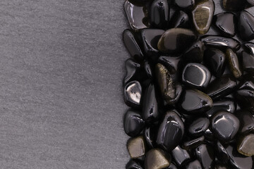 Gold obsidian jewel heap on black stone half background. Pile mineral pebbles texture. Place for...
