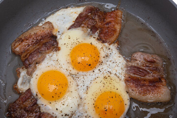 fried scrambled eggs with bacon in a frying pan