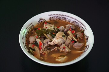 Spicy soup with pork leg, black background