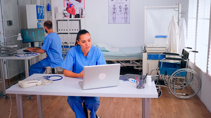 Physician assistant offering medical online advice for patient diagnosis using laptop. Practitioner...