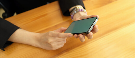 Businesswoman hands using mock up smartphone on wooden table